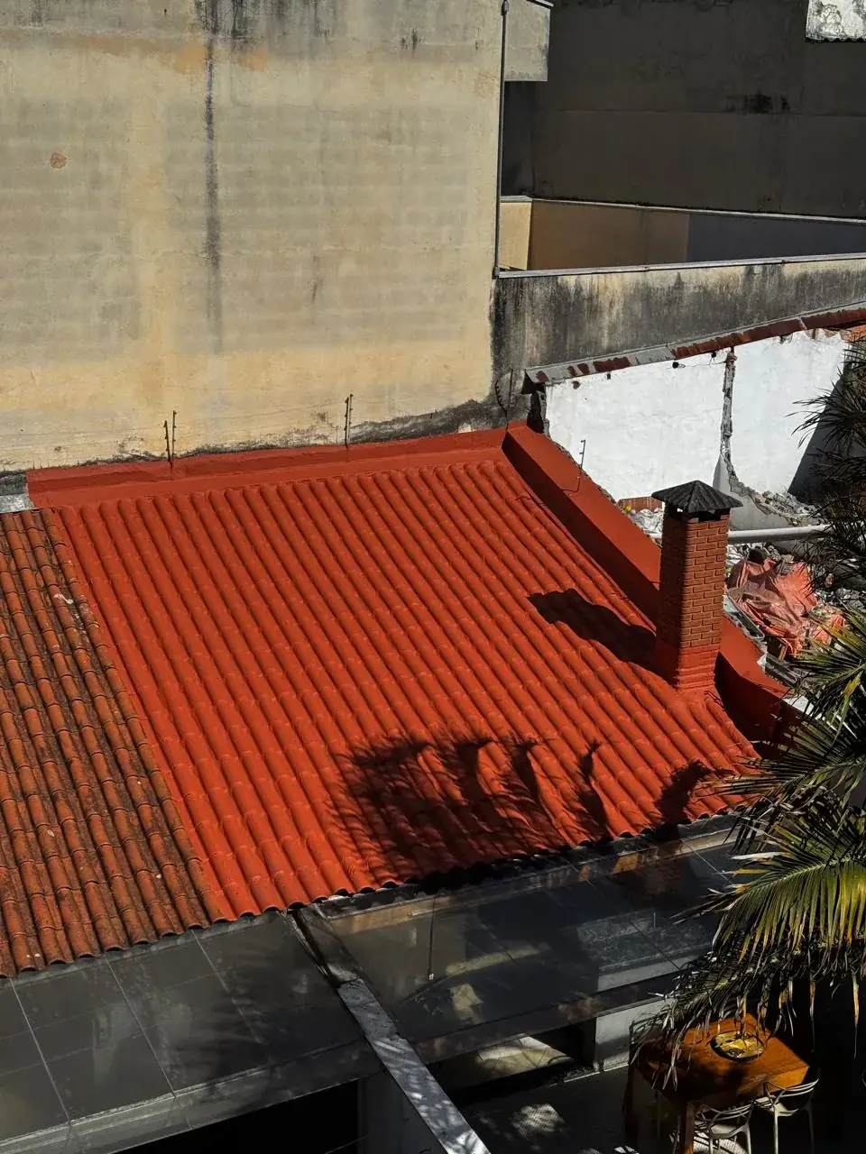 Telhado com revestimento vermelho, com o envelopamento contornando o duto da chaminé e o encontro com a parede