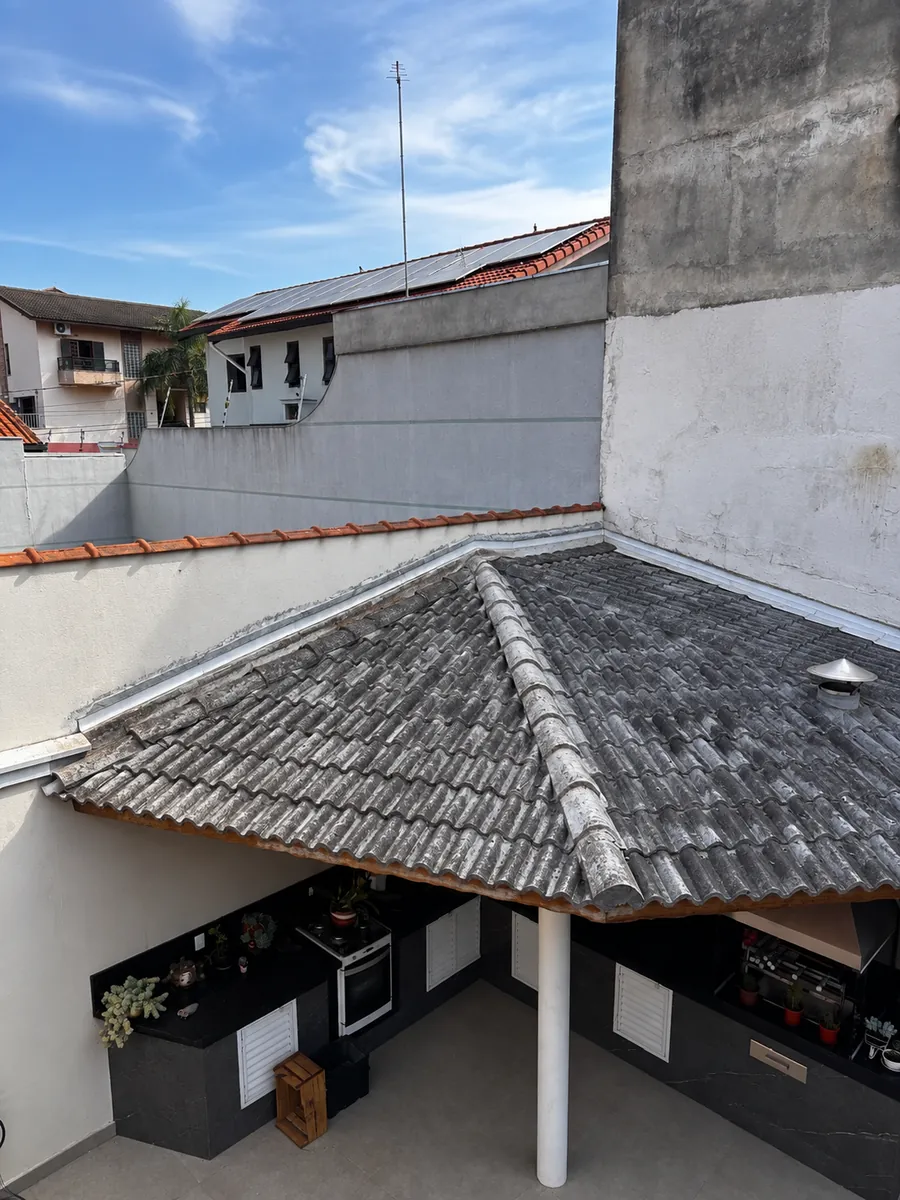 Telhado de telha cerâmica escurecido pelo tempo, com manchas e limo, antes do envelopamento
