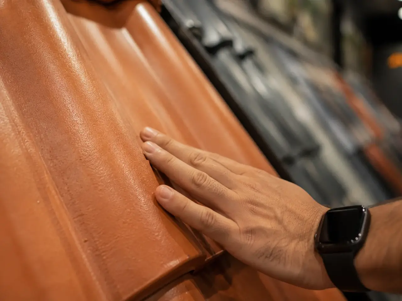 Mão tocando a textura de uma telha em exposição